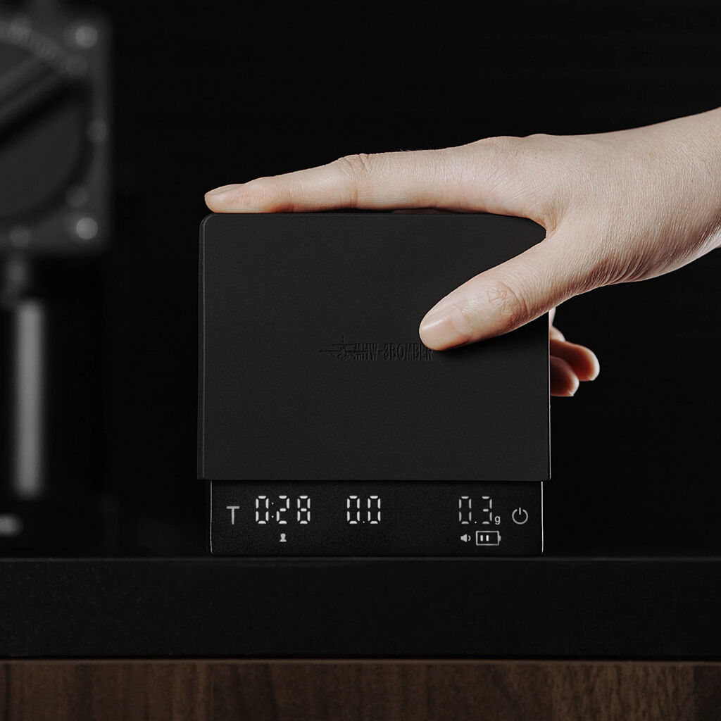 De MHW-3BOMBER koffieweegschaal 3.0 mini pro met hand om de grootte aan te geven